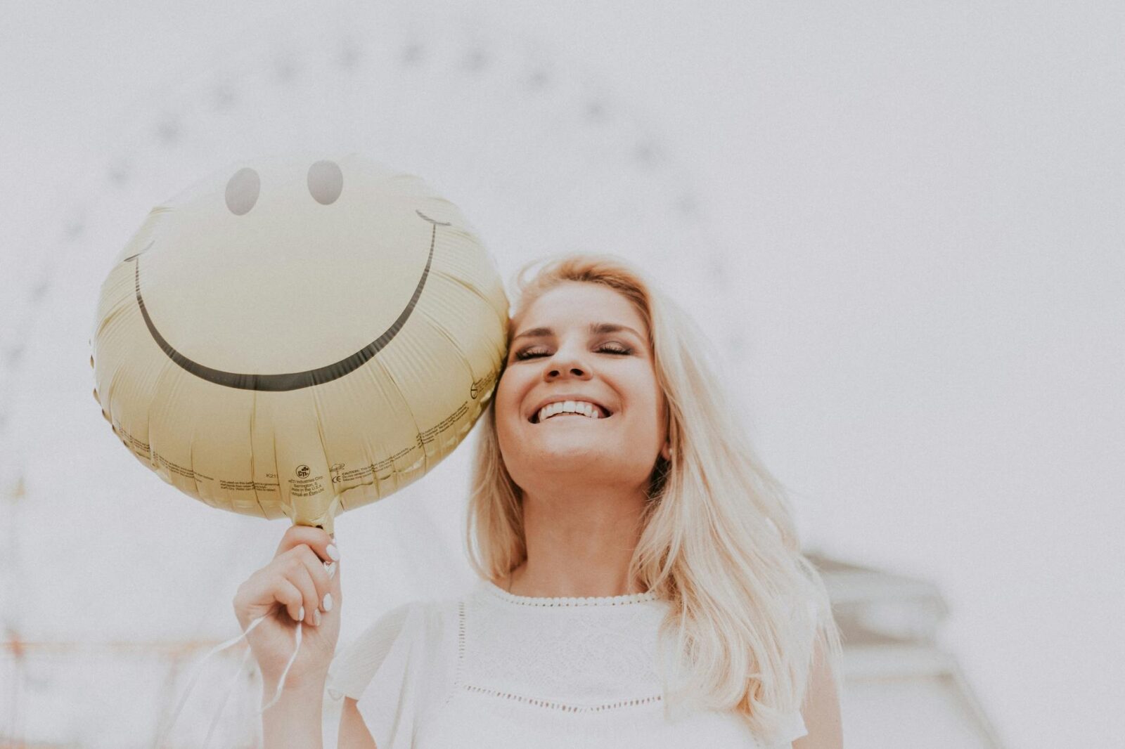 woman holding a smiley balloon How to Boost Self Confidence