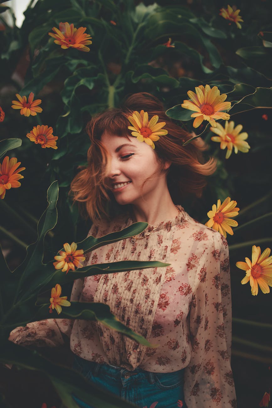 woman in pink floral shirt along with flowers Why Stress is Sabotaging Your Hair Health