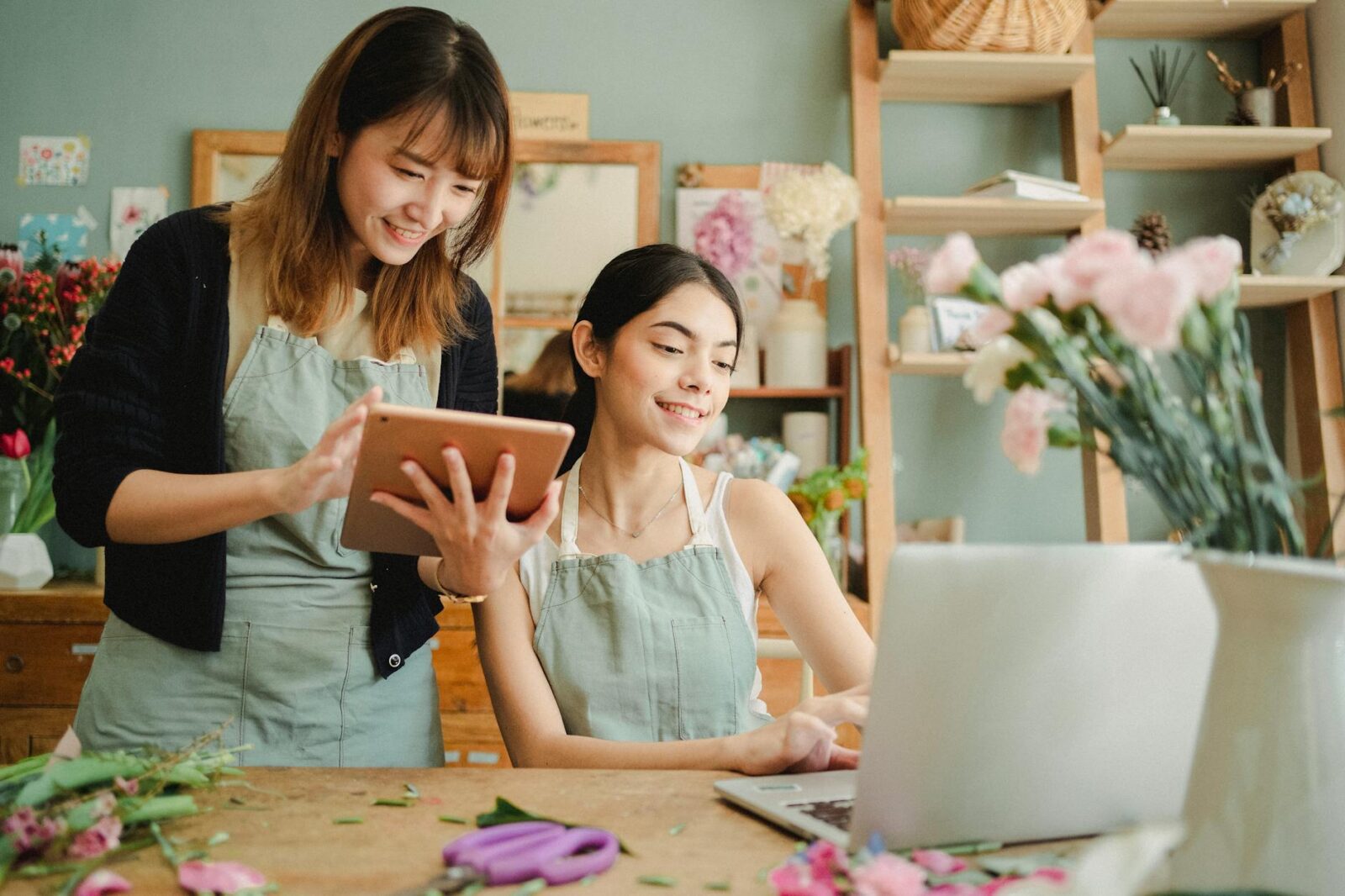 happy multiracial women working on gadgets in floral store Should you invest in a commercial property or rent?