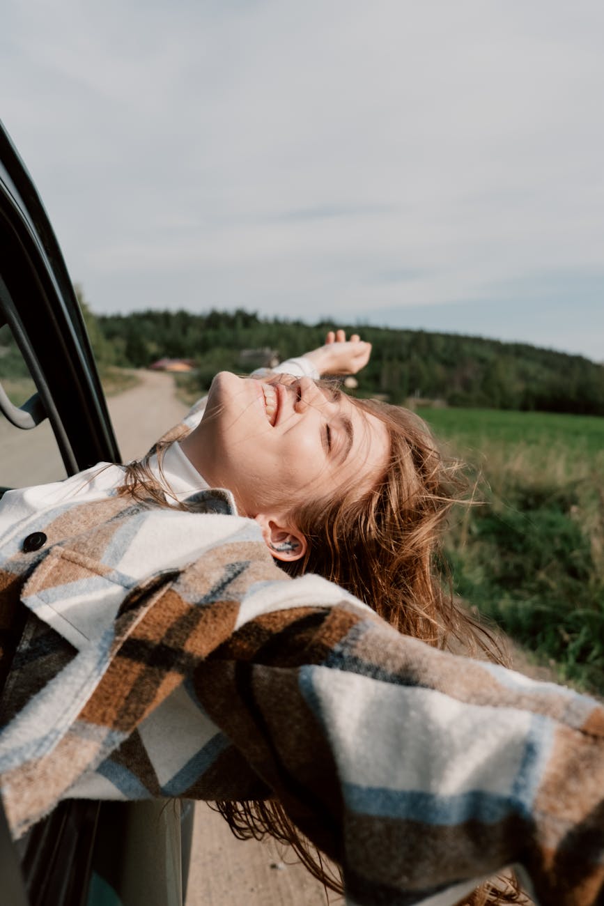 woman in plaid coat leaning out the car window The Biggest Life Milestones You Will Experience in Adulthood