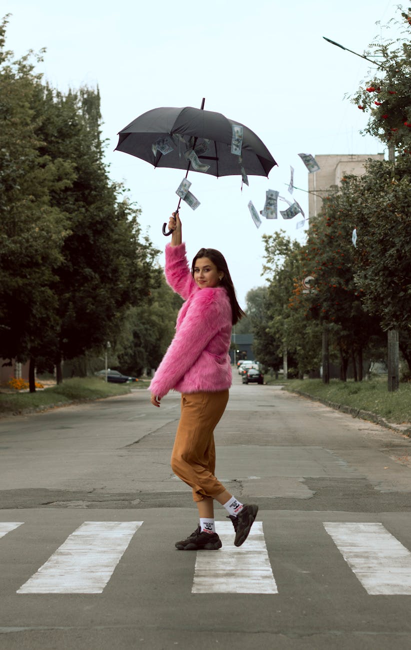 woman in pink long sleeve shirt holding umbrella walking on sidewalk The Ultimate Guide to Financial Independence