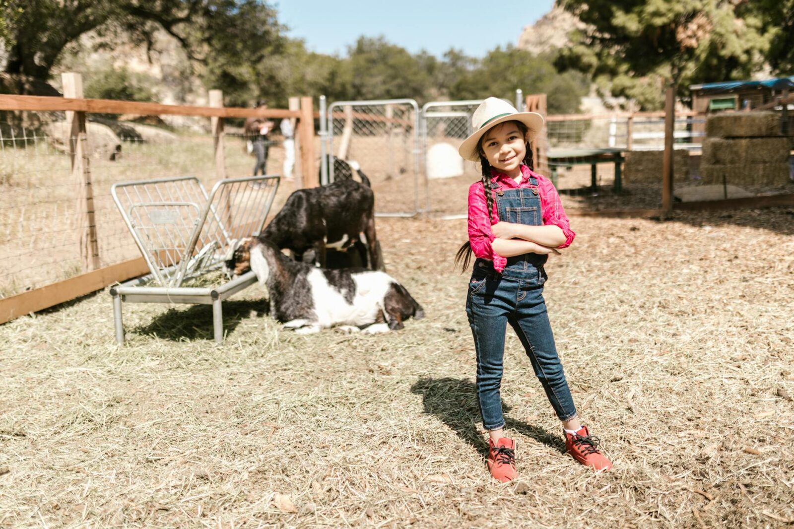 girl in pink shirt and denim overalls standing in the farm