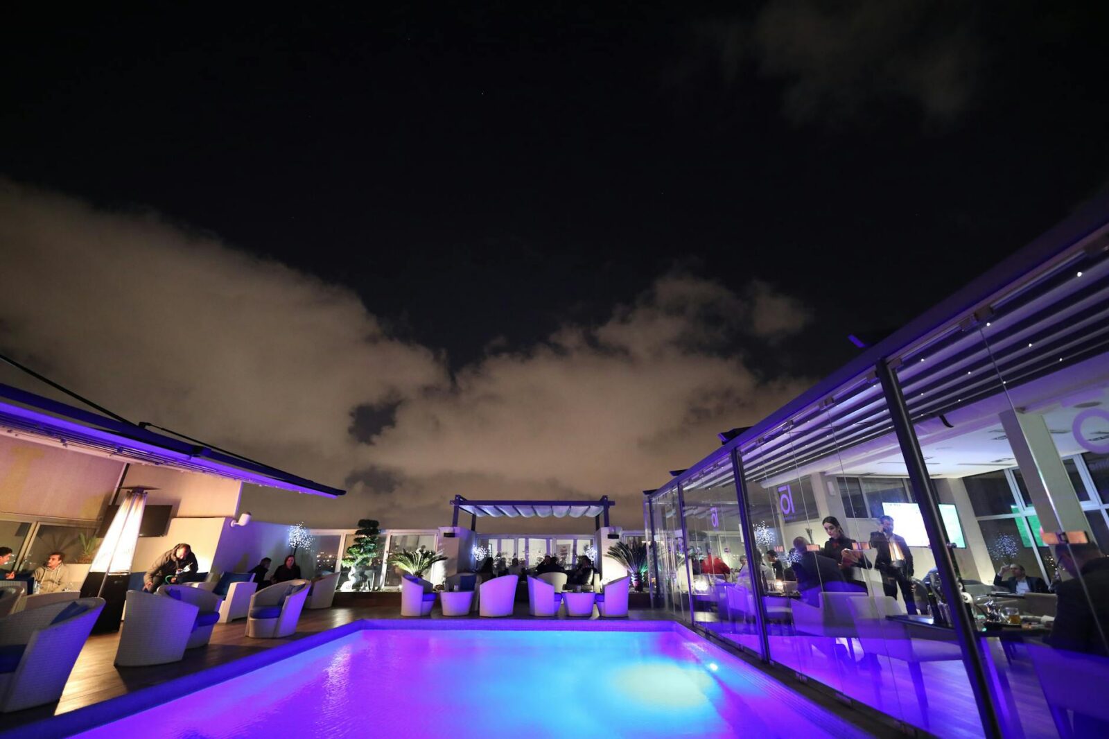 swimming pool surrounded with tables and chairs at night Poolside Perfection: How to Host a Pool Party Everyone Will Remember