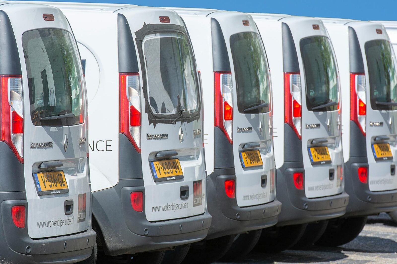 fleet of white vans parked in a row outdoors