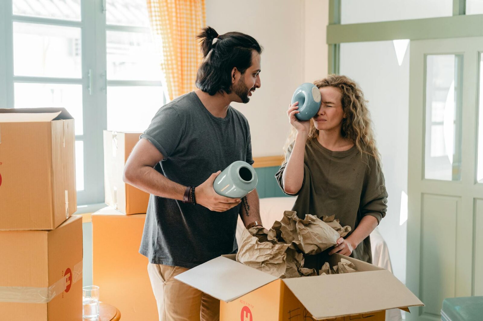 multi ethnic couple with ceramic vases and pile of cardboard boxes Moving House? Here’s How to Make Things Less Stressful
