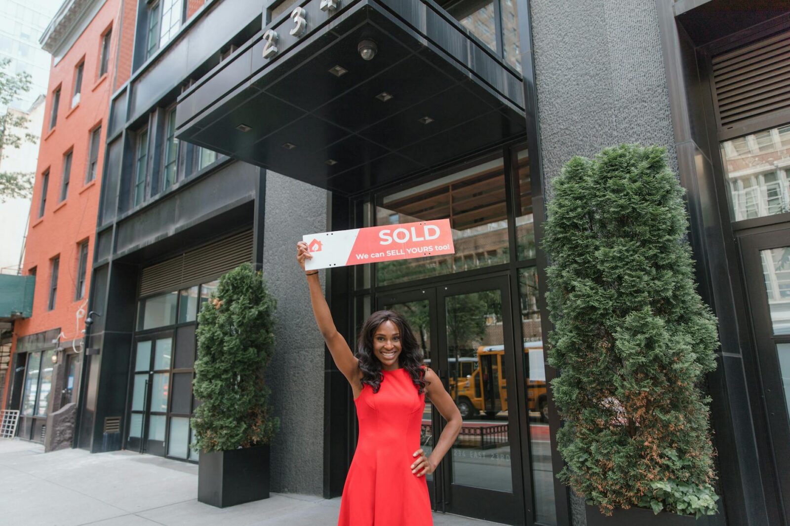 woman in red dress holding sold sign above her head Top Commercial Real Estate Investment Strategies: Upgrades That Maximize ROI