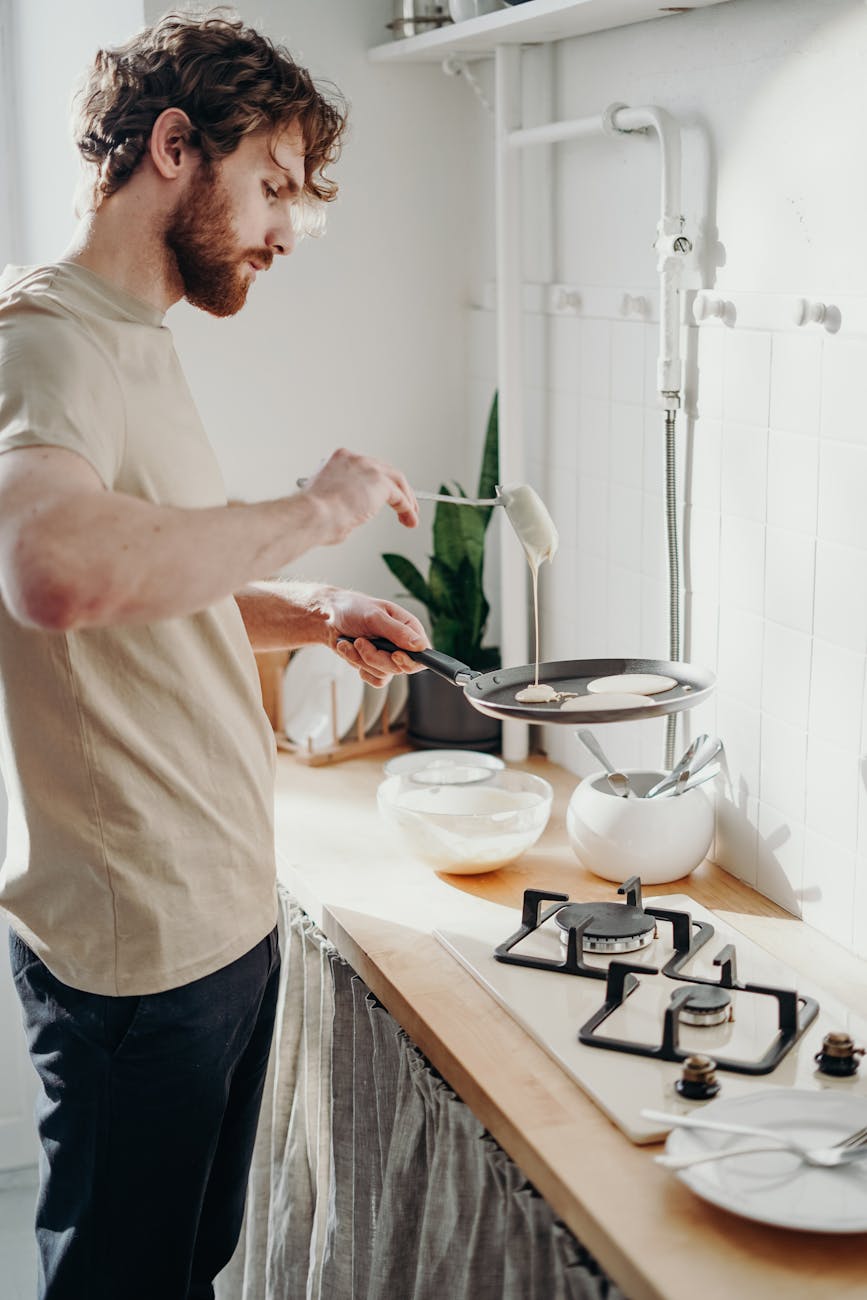 man holding frying pan and pouring milk How to Set Up a Kitchen From Scratch: STR Hosts & New Homeowners