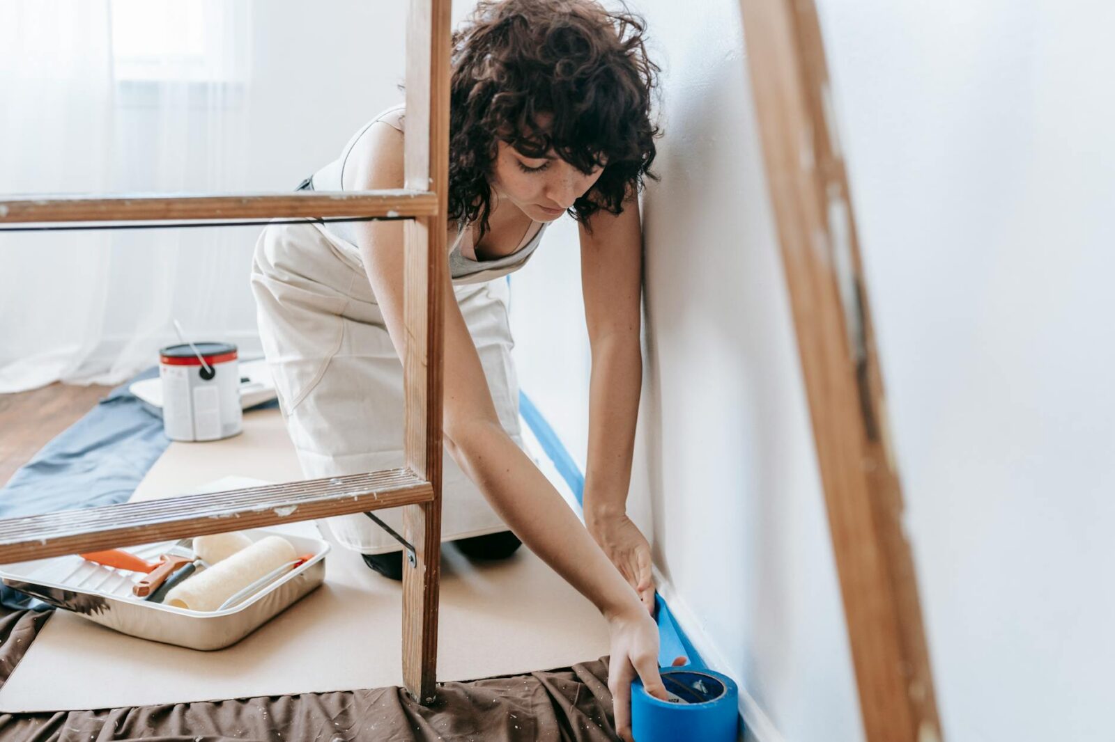 woman putting adhesive tape on wall Home Selling Mistakes That Cost You—And How to Avoid Them
