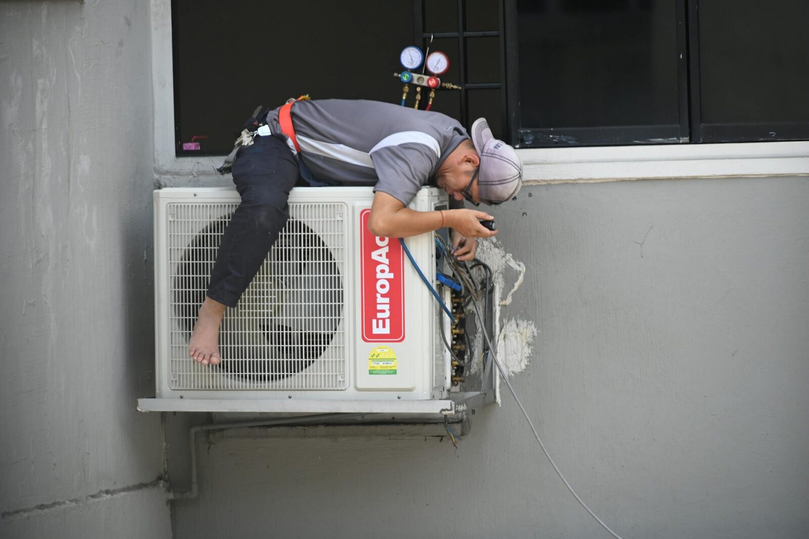 man in gray t shirt fixing the aircon Home Fixes You'll Want To Hire A Pro For