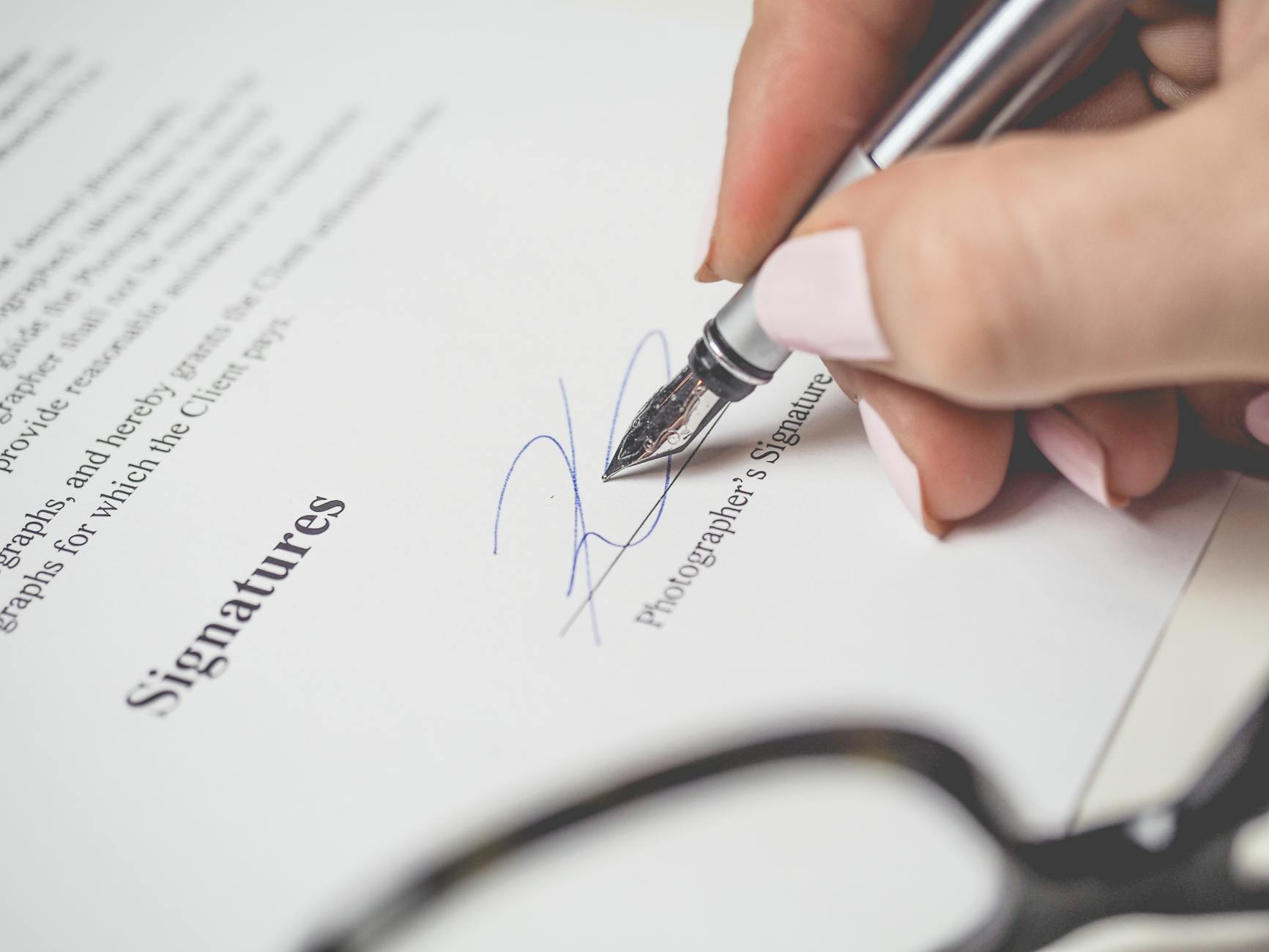 person holding silver pen signing photographers signature 5 Common Legal Issues Small Business Owners Face