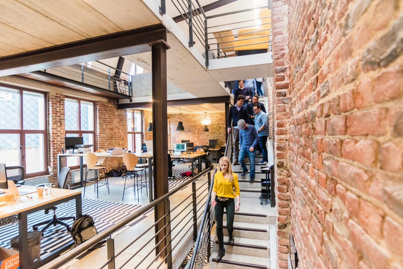 photo of woman in yellow top walking down stairs in a office room Signs You're Ready To Expand Your Business