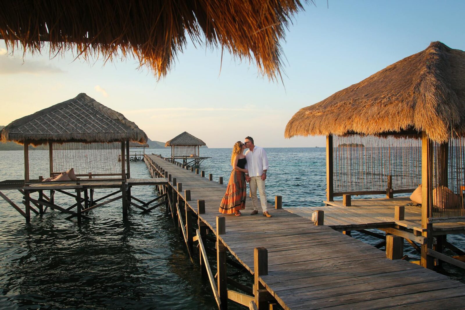 romantic couple on tropical pier at sunset