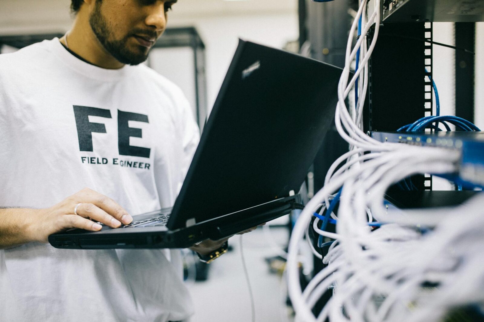 serious ethnic field engineer examining hardware and working on laptop 6 Ways Preventative Maintenance Saves Your Business Money