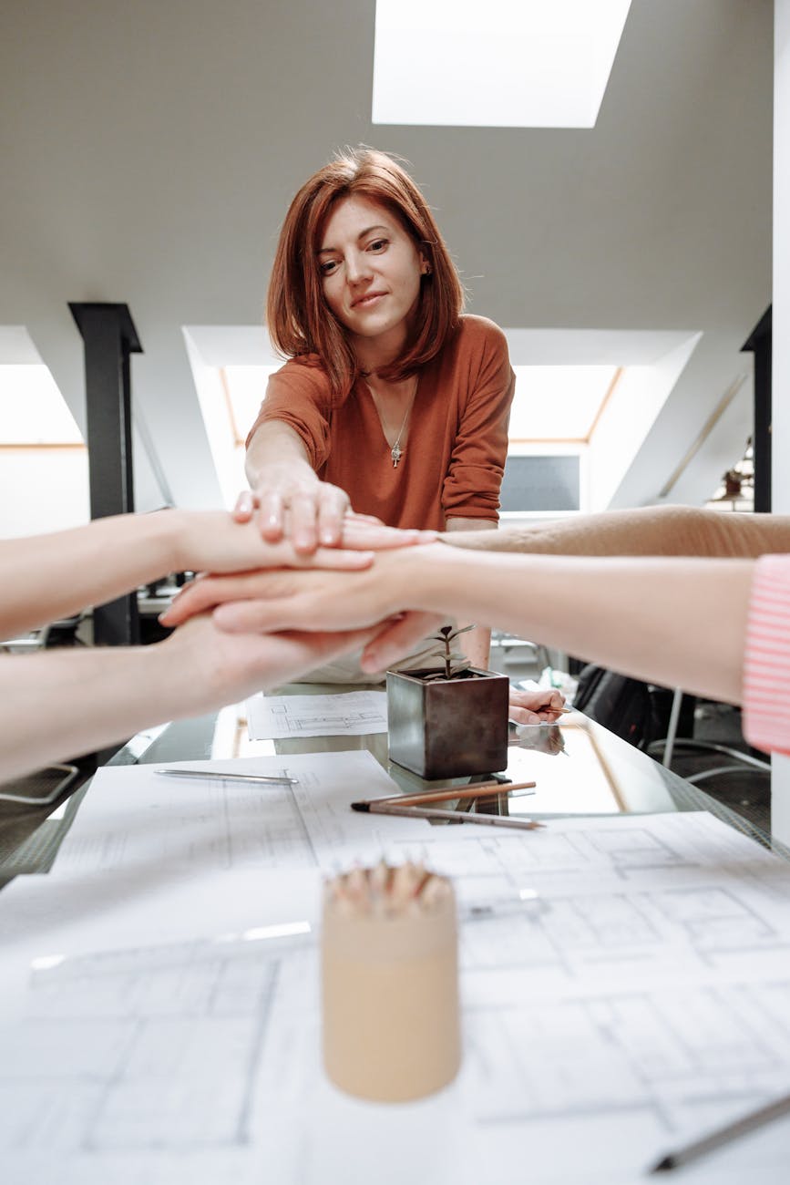 a group of people with their hands together 4 Top Traits Of Exceptional Business Leaders