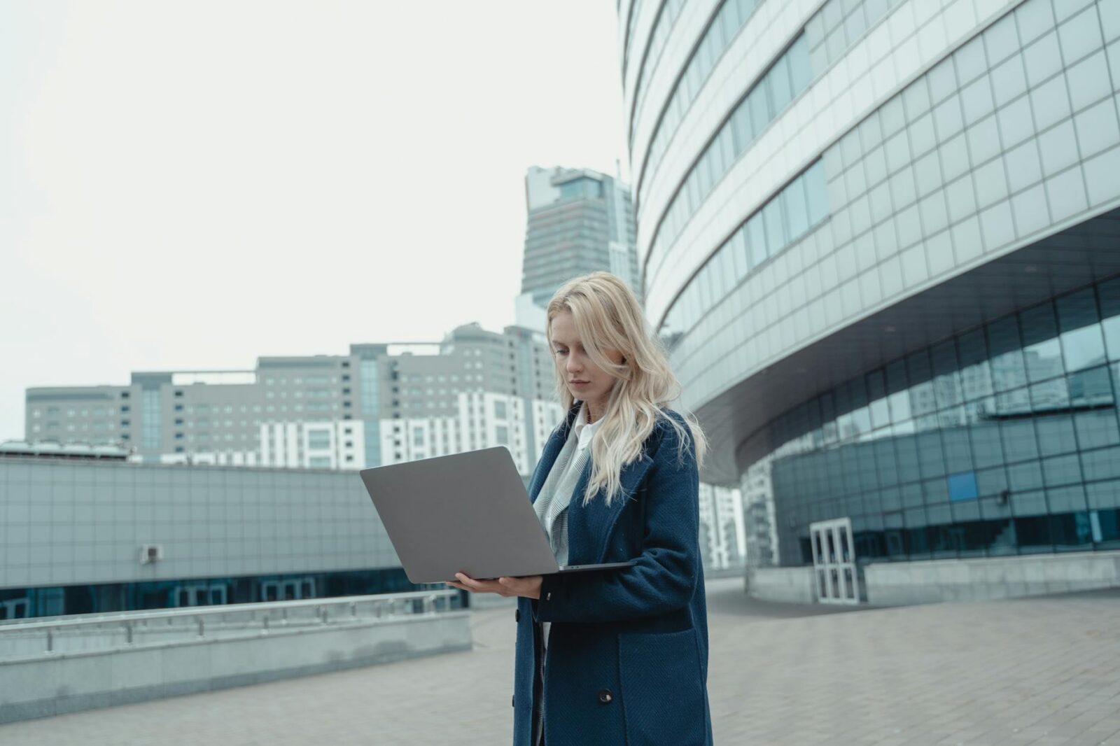 woman in blue coat standing near the high rise building