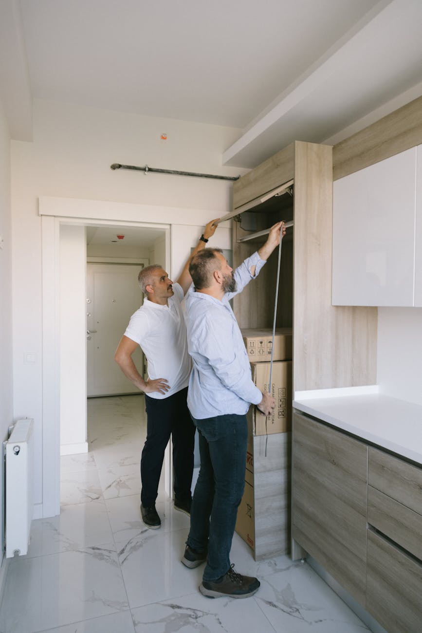 man measuring a cabinet with another man DIY Disasters and How to Avoid Them