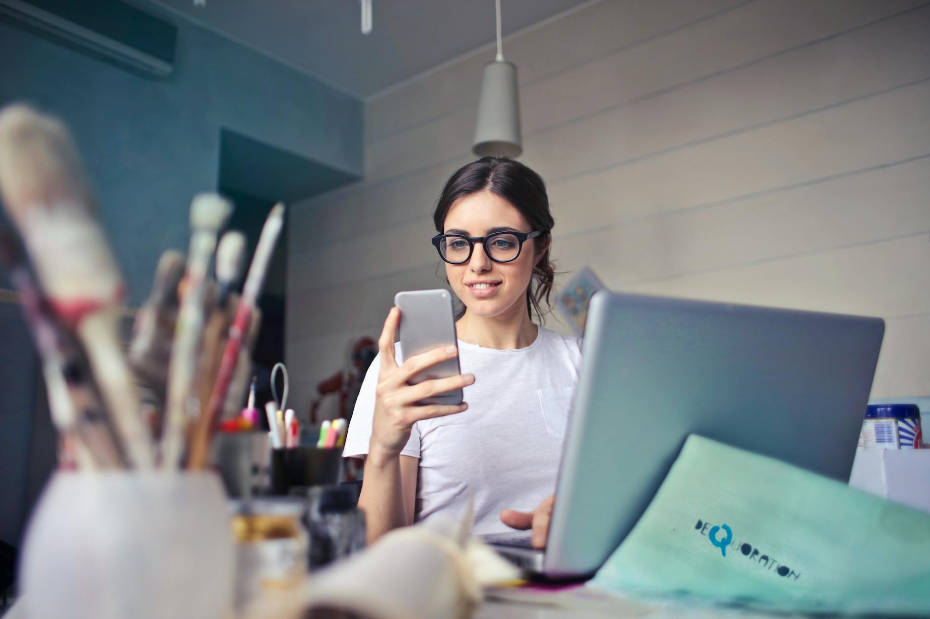 woman in white t shirt holding smartphone in front of laptop 5 Common Legal Issues Small Business Owners Face