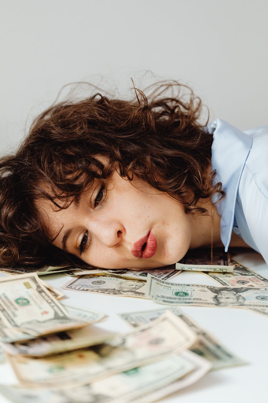 close up shot of a curly haired woman lying her head on paper money 7 Foolproof Strategies to Tackle Your Financial Stress