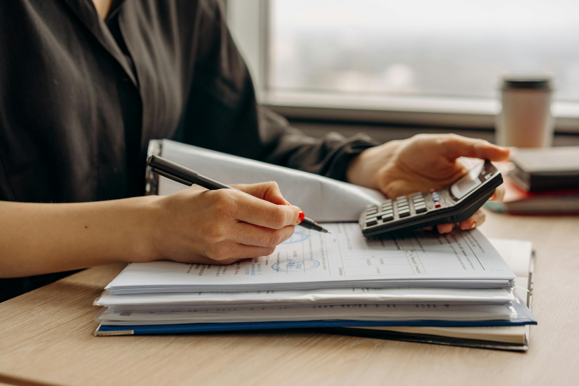 person in long sleeve shirt holding a calculator The Importance of a Small Business Emergency Fund