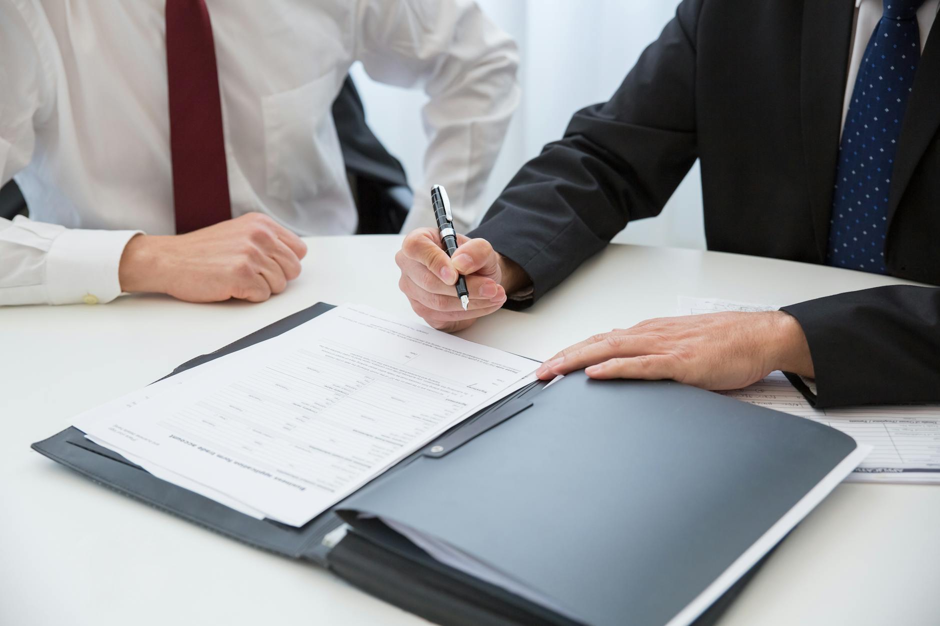 a person in black suit holding a pen near the documents on the table Avoid These Legal Compliance Dangers When Starting Your Business