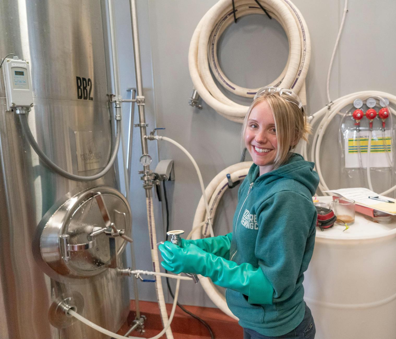 woman wearing pair of teal rubber gloves standing near white barrel The Role of Workplace Safety in Driving Business Success