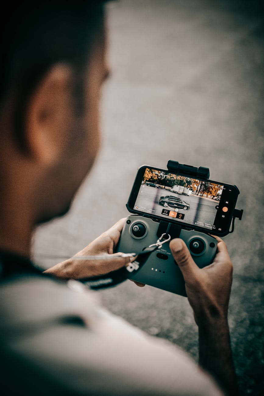 a man using a controller of a drone with a smartphone as a monitor The Business Owner's Guide to Video Surveillance & VMS for Company Security