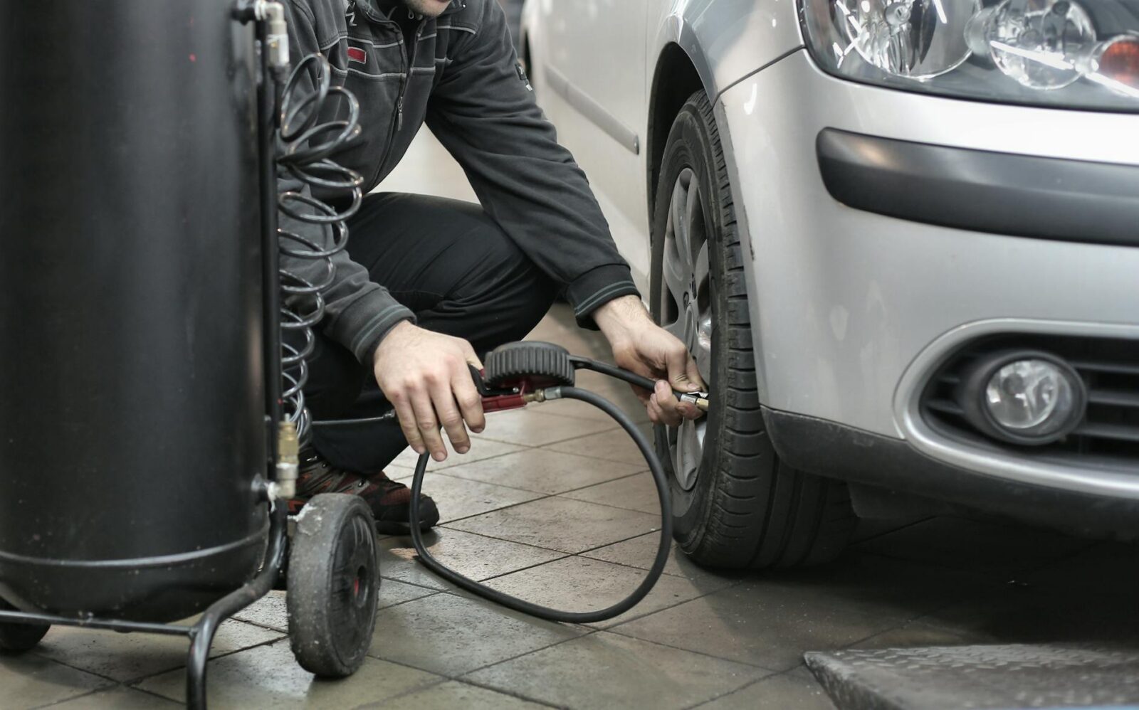 man in black jacket and black pants sitting near silver vehicle What Businesses Need to Know About Driver Safety Compliance
