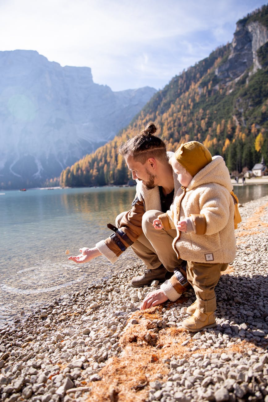 man in brown coat sitting on rocky shore 7 Fun Family Vacation Ideas Your Kids Will Love