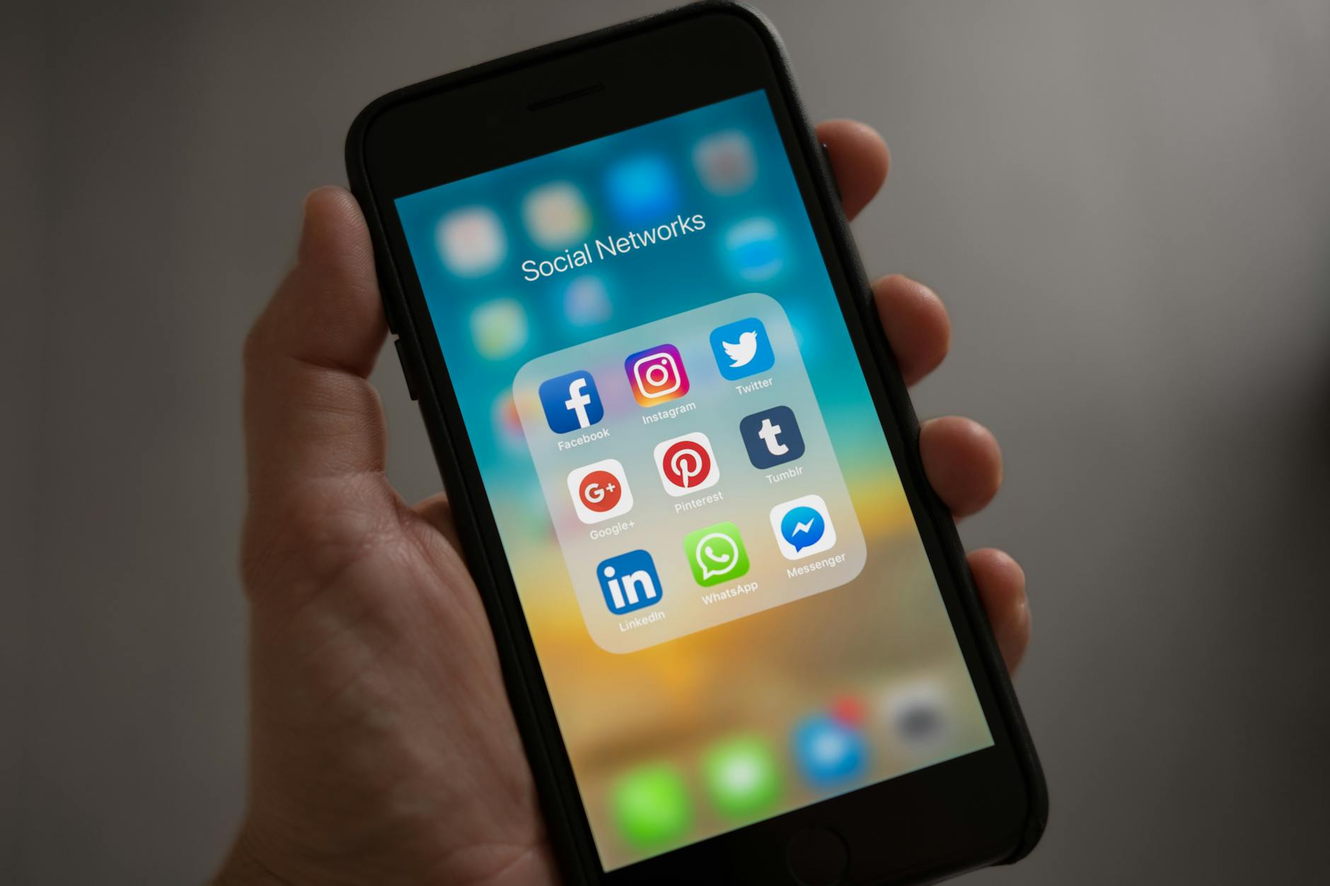 person holding iphone showing social networks folder 5 Essential Strategies to Build Brand Visibility Long-Term