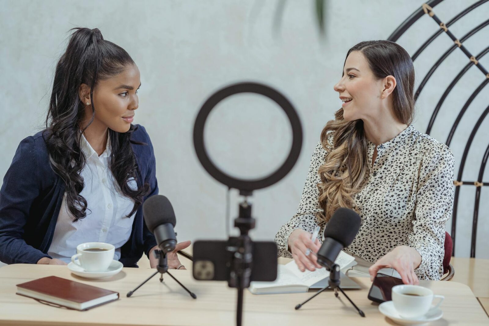 smiling woman interviewing black female guest and recording video 10 Proven Ways to Increase Your Business Visibility Online and Offline