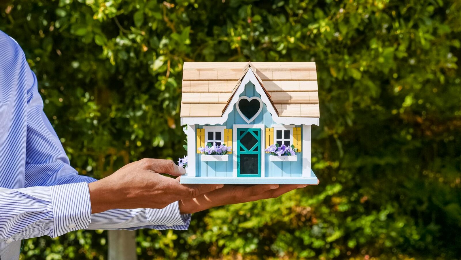 person holding a miniature wooden house