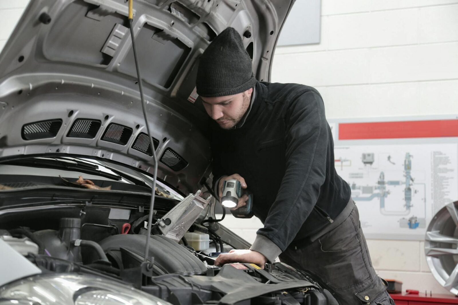 man in black jacket and black knit cap inspecting car engine What to Do After a Car Accident: Step-by-Step Checklist