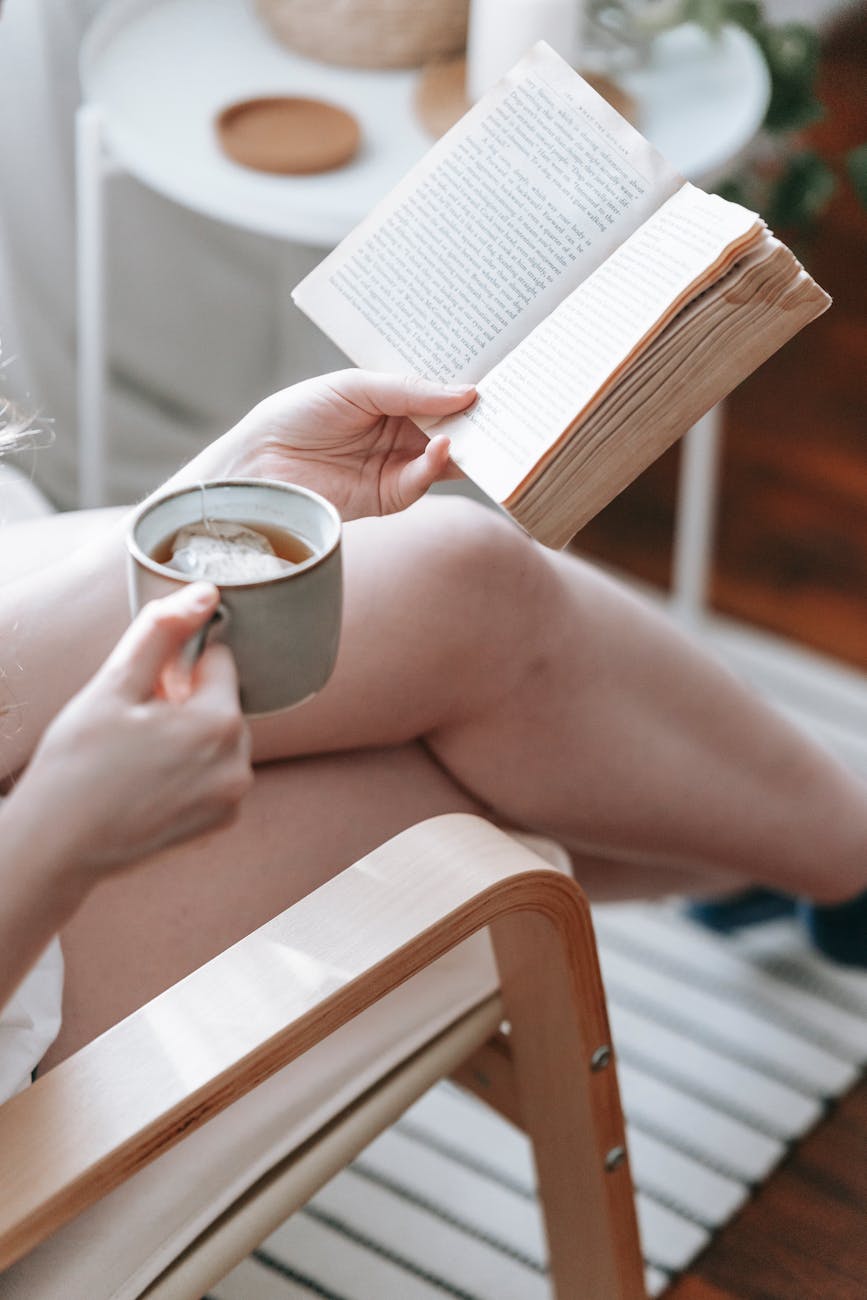 woman reading book and drinking tea at home Entrepreneurship 101: How To Make Running A Business Feel Less Stressful