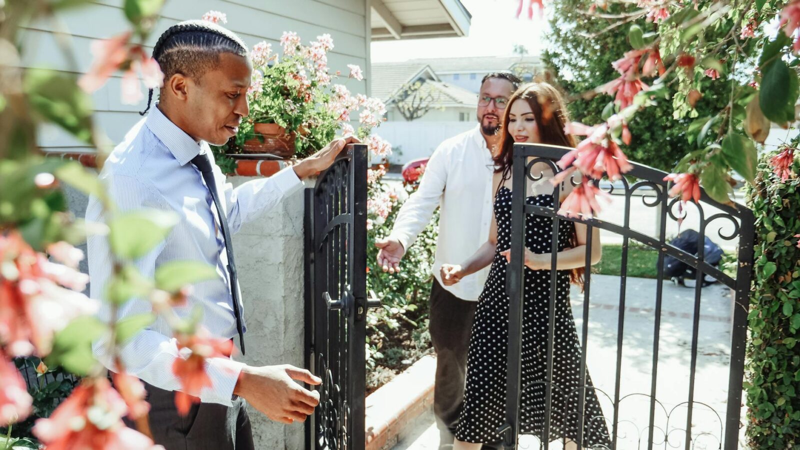 man in dress shirt holding the gate for a couple Top Tips for Finding the Perfect Place to Live