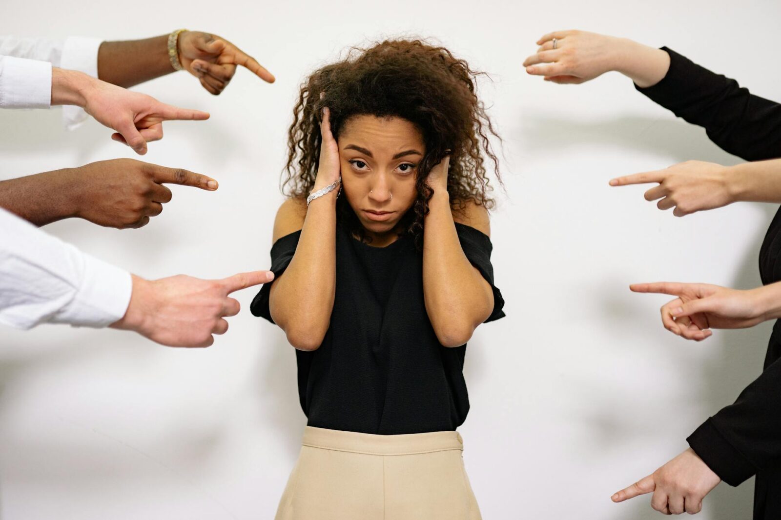 people pointing fingers at a stressed woman Before Offering Mental Health Perks, Fix These Workplace Issues