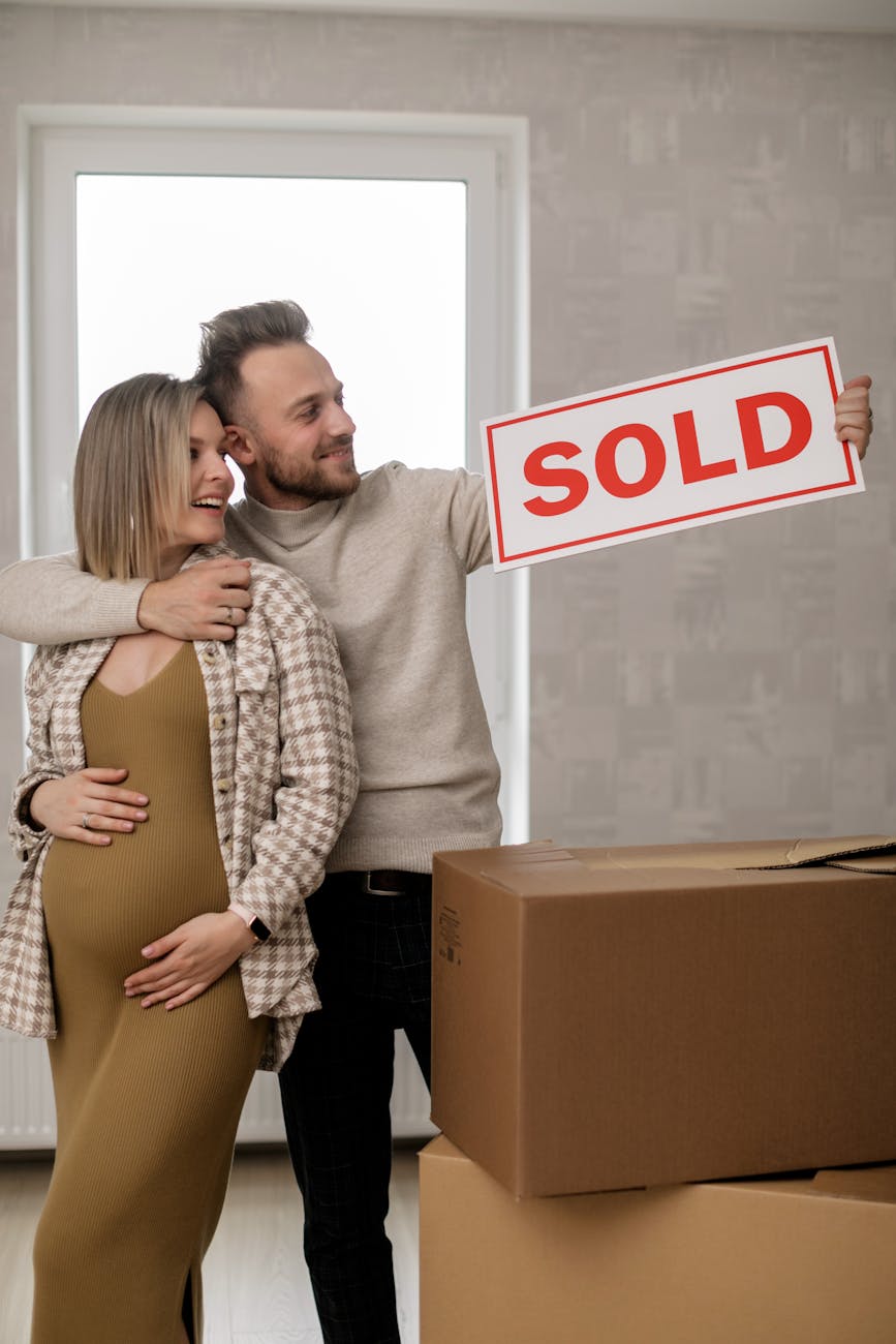 a man hugging a pregnant woman while holding a signage Selling a House Fast Doesn’t Have to Be Stressful