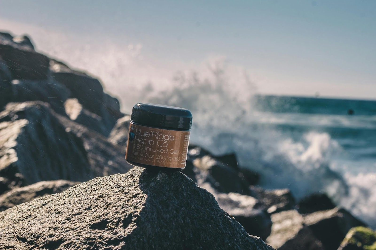 A jar of CBD-infused gel from Blue Ridge Hemp Co. is placed on a rock by the ocean, with waves crashing in the background. What Goes Into Product Design? 6 Key Steps to Create a Successful Product