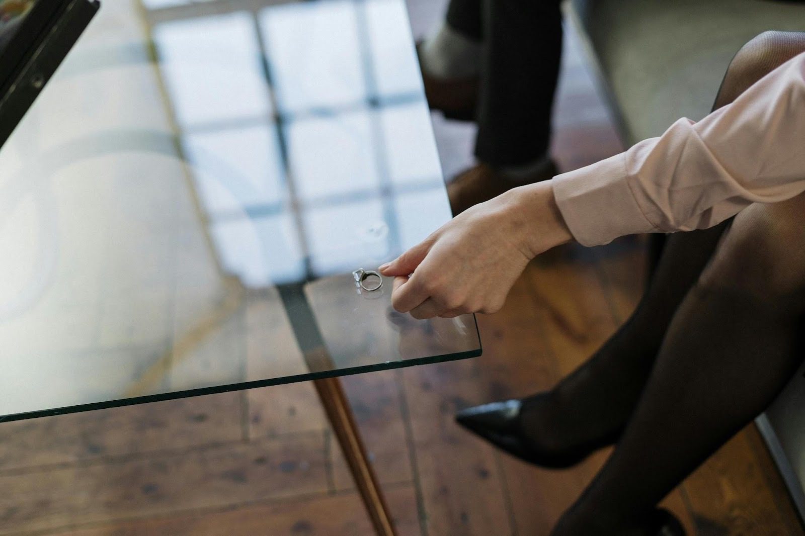 A person placing a ring on a glass table, suggesting themes of contemplation and emotional transitions related to divorce. How to Navigate Divorce: Emotional, Legal, and Financial Realities