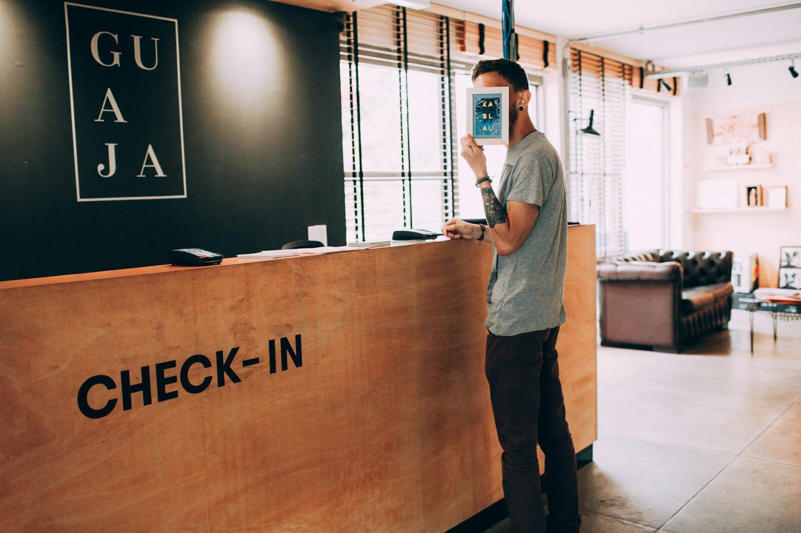 man covering face with frame at the check in counter of a hotel lobby How to Increase Hotel Revenue: 3 Practical Tips for Sustainable Growth