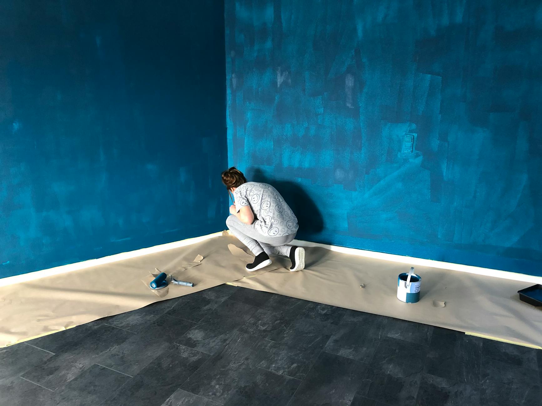 woman in gray shirt and gray pants painting the walls 8 Things You’ll Regret Not Doing Before Moving Into Your New Home