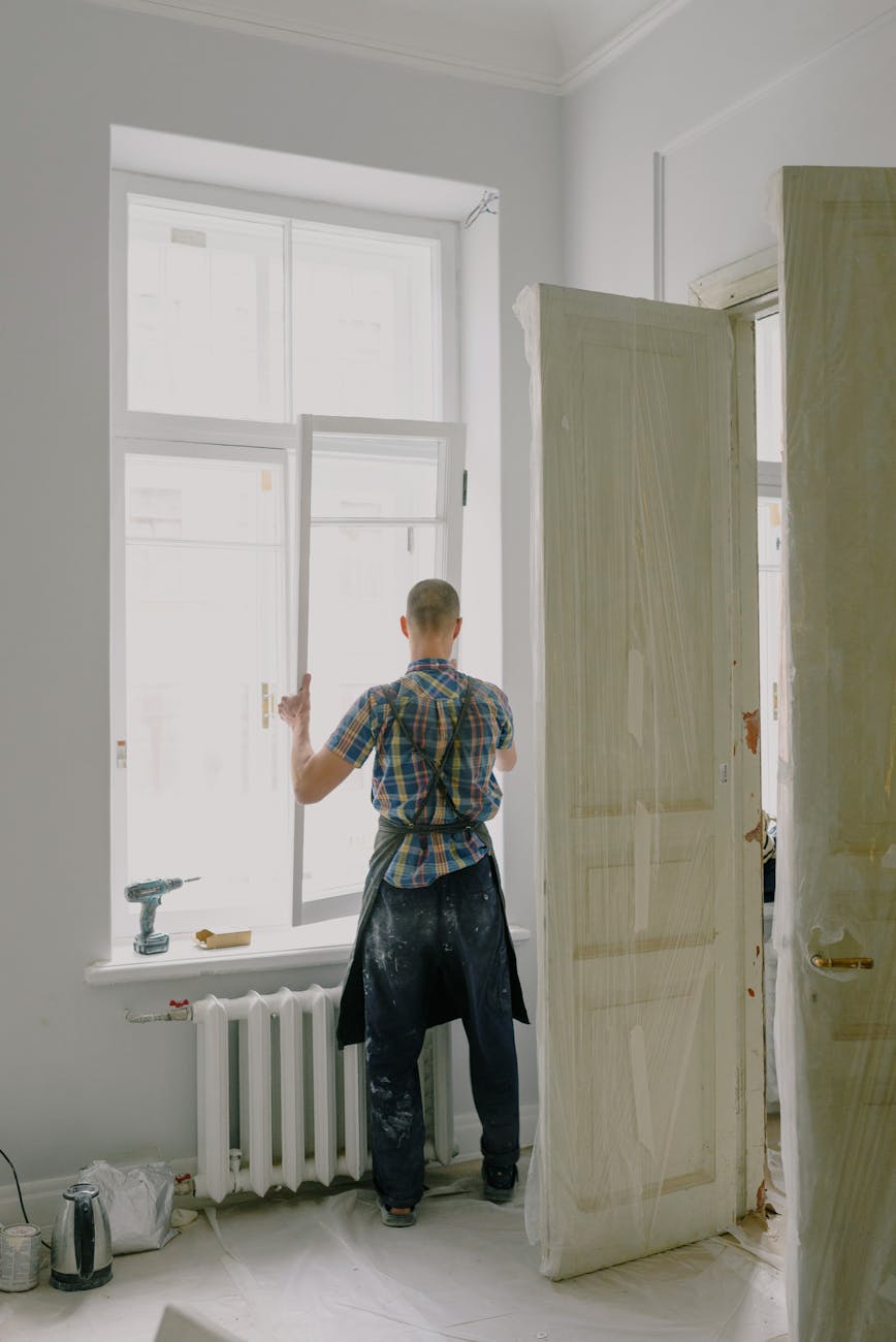 faceless handyman mounting window in new house 8 Things You’ll Regret Not Doing Before Moving Into Your New Home