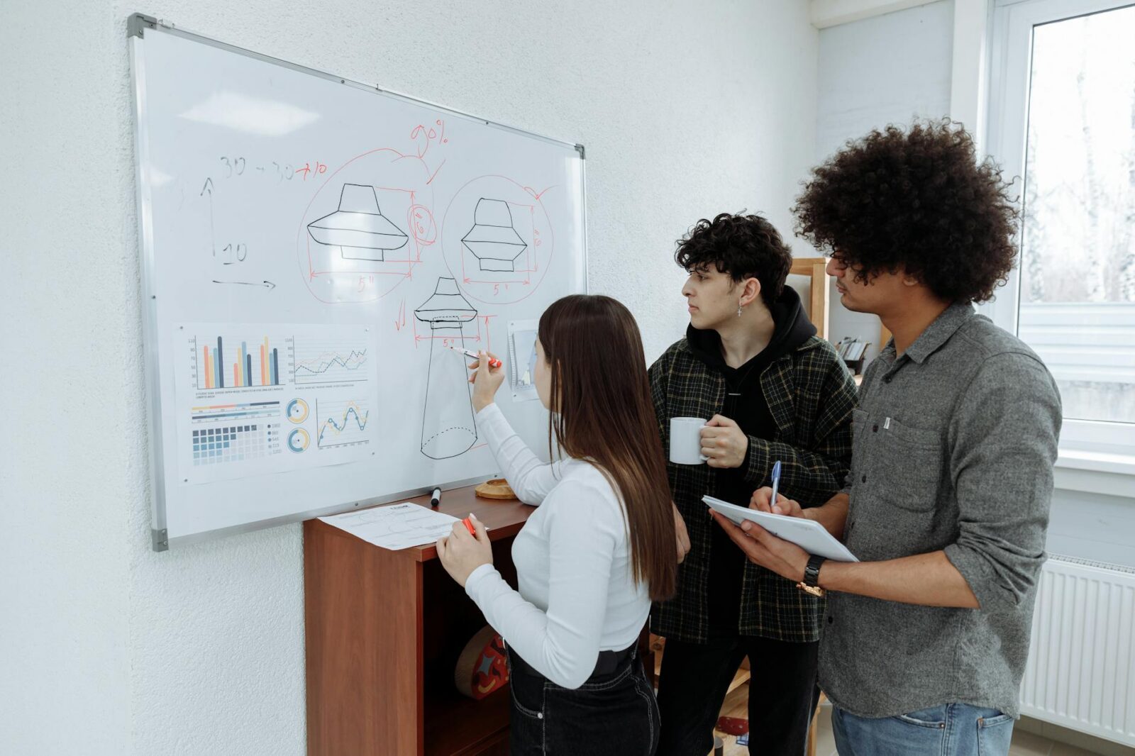 colleagues brainstorming with a whiteboard What Goes Into Product Design? 6 Key Steps to Create a Successful Product
