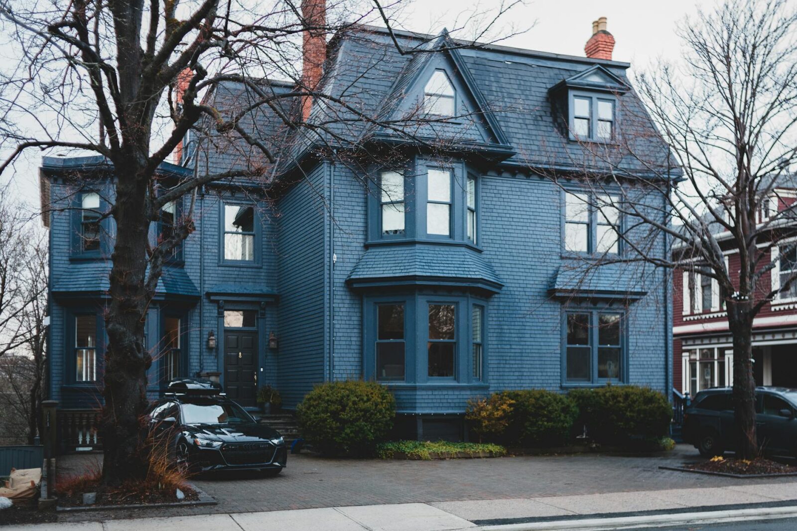 blue modern building with bushes and trees and cars What Would You Do With $100,000? Tips From a Pro Investor Long Term Renatl Investing