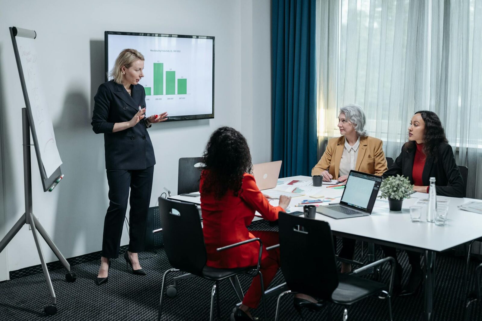 woman in black suit presenting graphs in a meeting 10 Steps to Build a Successful Writing Business