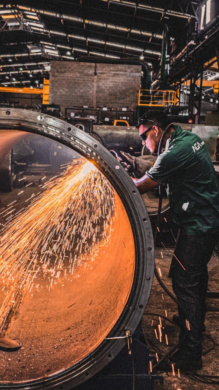 industrial worker using grinder inside factory How Automation Is Transforming Heavy Metal Fabrication