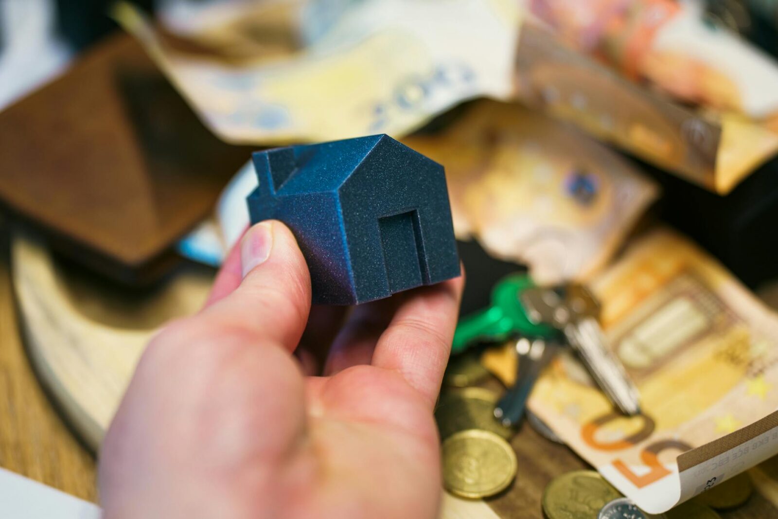 hand holding model house with money and keys The Truth About Real Estate Investing: Profit, Pitfalls, and Smart Strategies