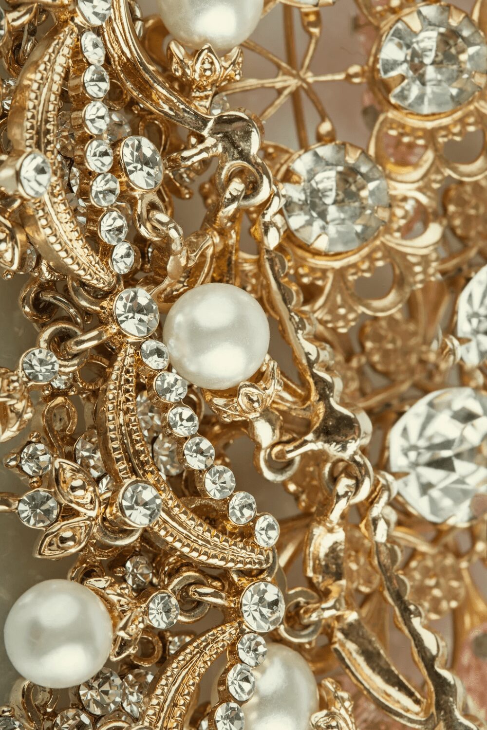 Close-up view of ornate gold jewelry featuring intertwined designs, sparkling rhinestones, and a single pearl, showcasing intricate craftsmanship. Best Diamond Gold Stud Earrings for Women