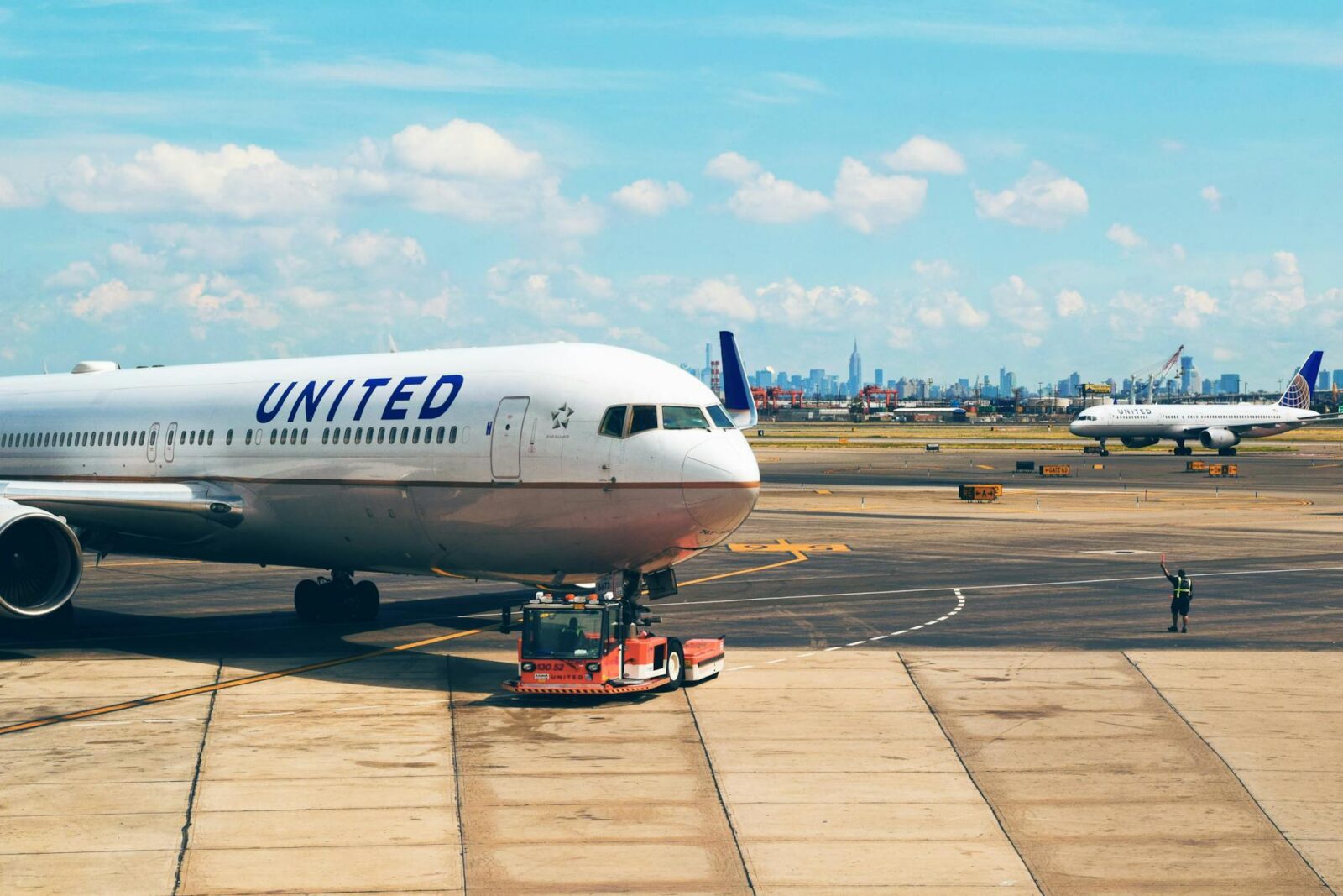 white airplane near man in green vest Best Airlines to Fly Business Class to the UK from the USA (2026 Guide)