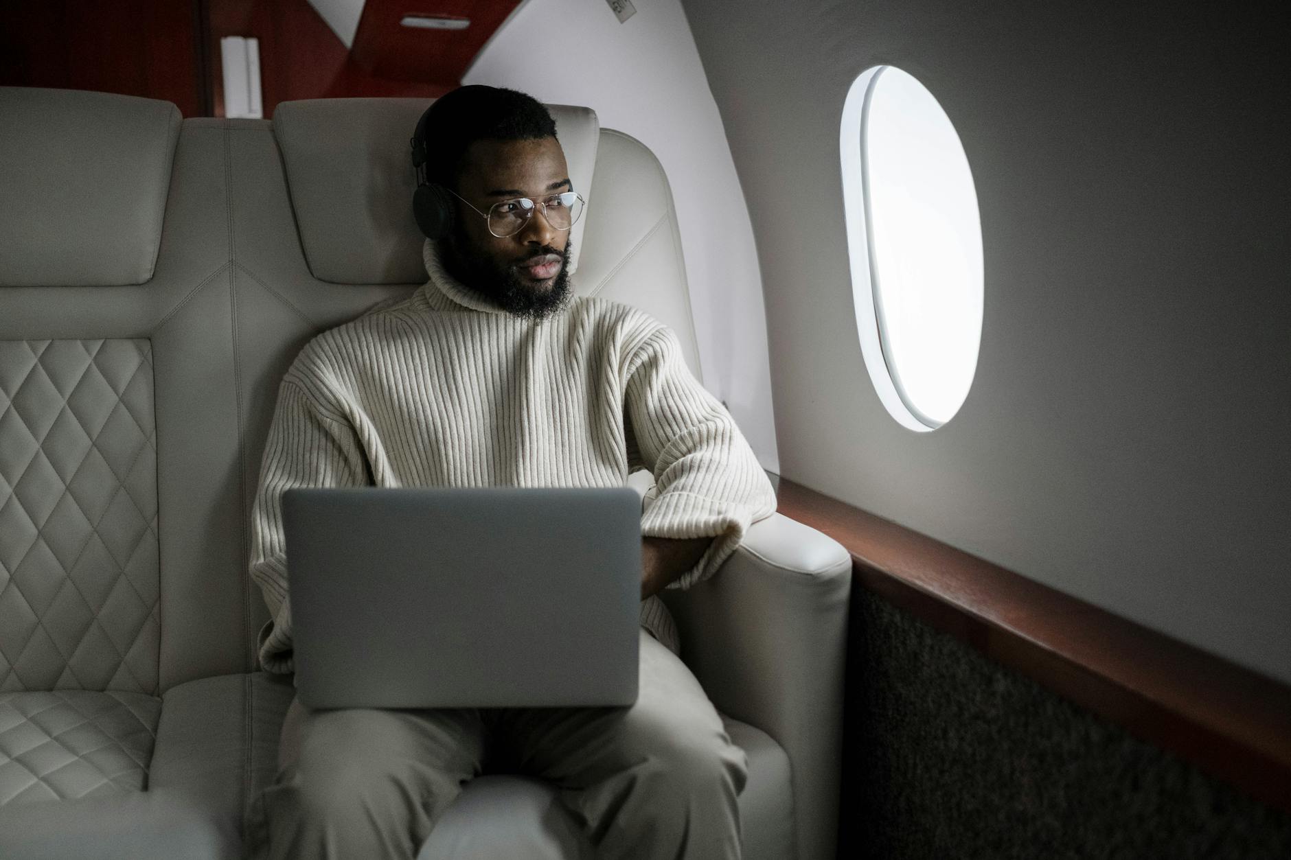 man in white sweater sitting on couch using macbook Best Airlines to Fly Business Class to the UK from the USA (2026 Guide)